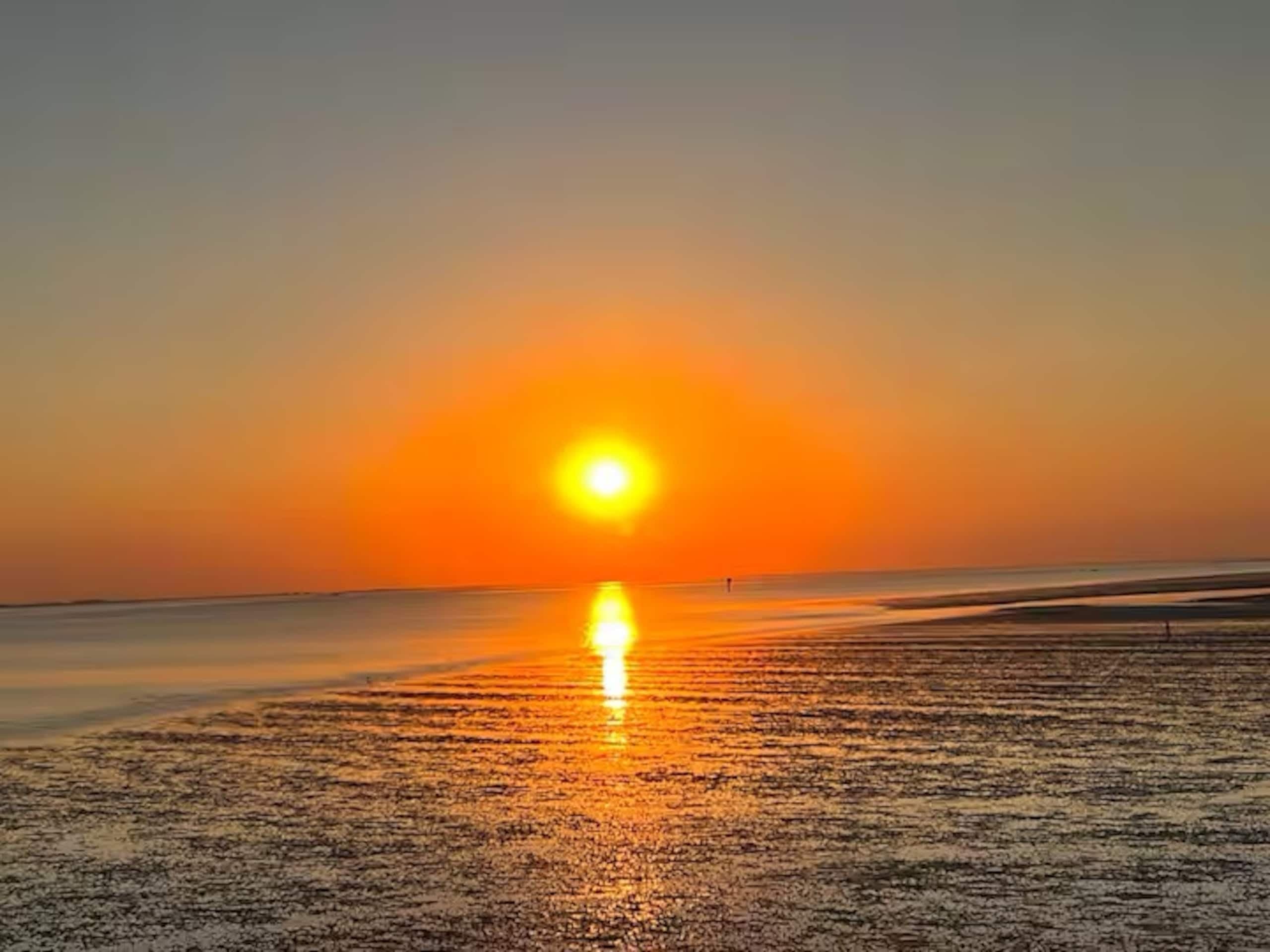 De zon zakt in het water, met het droogvallende wad ervoor